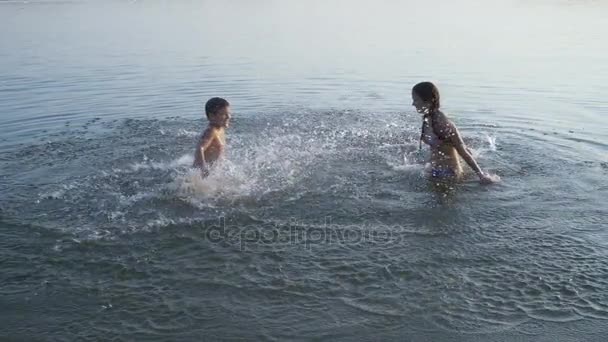 Dos niños salpicando agua en el río al atardecer — Vídeos de Stock