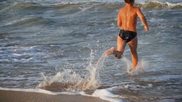 Teenage boy running to the sea from beach — Stock Video