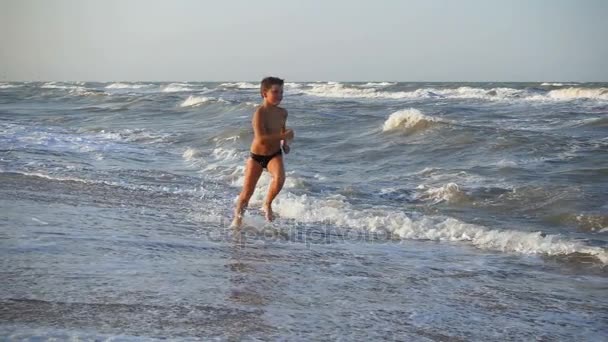 Sonriente chico corriendo en el mar surf — Vídeos de Stock