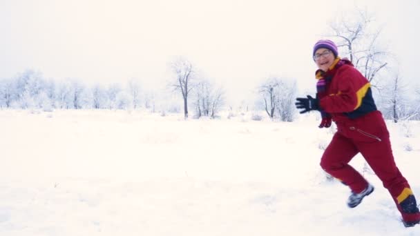 Ευτυχισμένη γυναίκα τρέχει στο χειμωνιάτικο τοπίο — Αρχείο Βίντεο