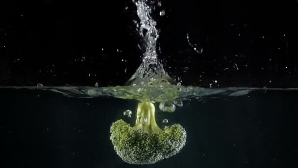 黒い背景に水に落ちるブロッコリー — ストック動画