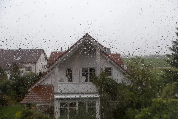 Gotas de chuva no vidro da janela com vista para a casa vizinha — Fotografia de Stock