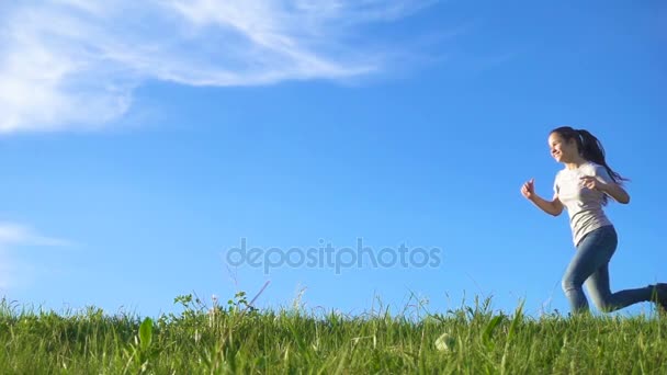 Menina feliz correndo na colina de grama verde contra o céu azul — Vídeo de Stock