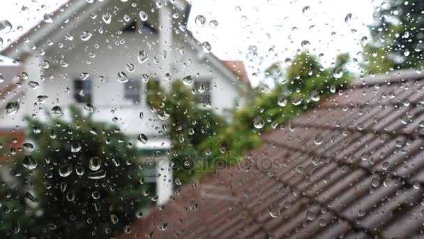 Σταγόνες βροχής στο γυάλινο παράθυρο με θέα προς το σπίτι του γείτονα — Αρχείο Βίντεο