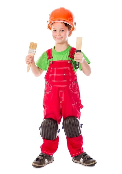 Pequeno construtor em capacete com pincel e espátula — Fotografia de Stock
