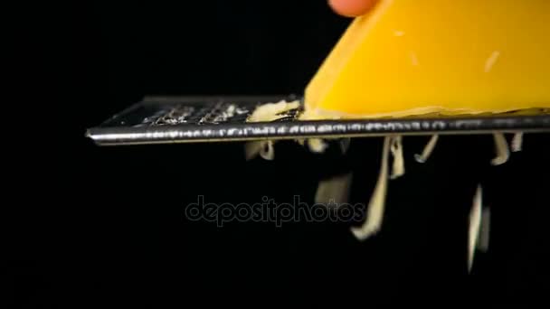 Frotando a mano el queso de rallador de metal sobre fondo negro — Vídeo de stock