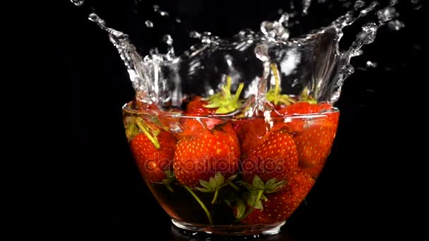 Falling strawberries on glass bowl with water splash — Stock Video