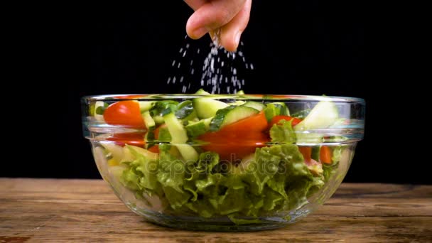 Agregar una sal a la ensalada en un tazón de vidrio — Vídeo de stock