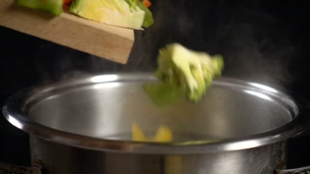 Добавление овощей к кипящей воде в кастрюле, замедленная съемка — стоковое видео