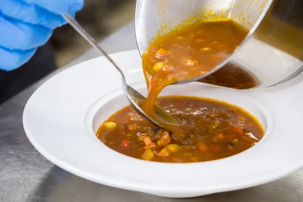 Verter la sopa de la sartén en un tazón con un cucharón — Foto de Stock