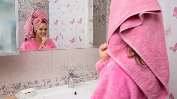 Fiatal lány, takarítás a fogak, a fürdőszobában fürdőköpeny — Stock videók