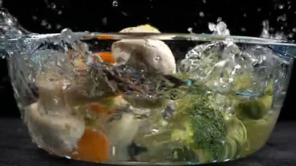 Légumes tombants à la casserole en verre avec éclaboussure d'eau — Video