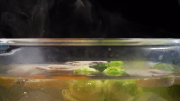 Kochendes Wasser mit Dampf, Gemüse in Glaspfanne kochen — Stockvideo