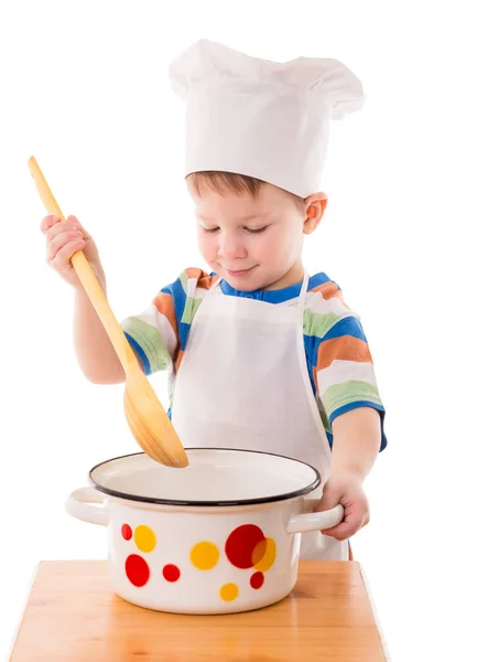 Menino com uma grande concha na mão está misturando algo da panela — Fotografia de Stock