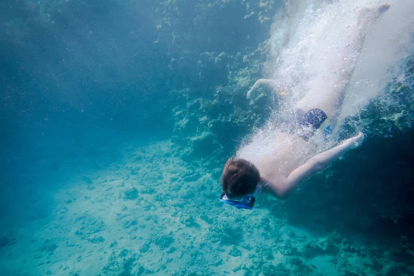 Jongen in zwemmen masker duiken in de rode zee in de buurt van coral reef — Stockfoto