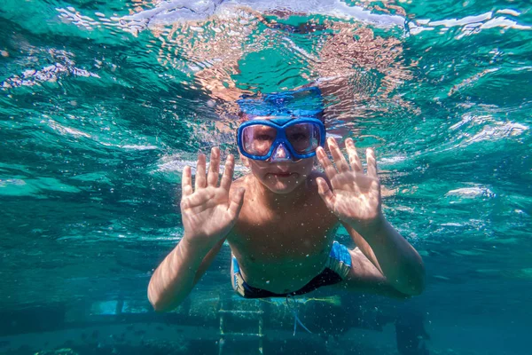 Мальчик в плавательной маске ныряет в Красном море возле понтона — стоковое фото