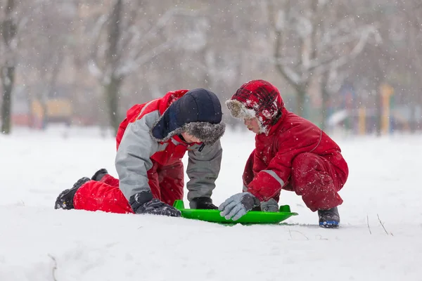Twee gelukkige jongens spelen met dia op besneeuwde landschap — Stockfoto