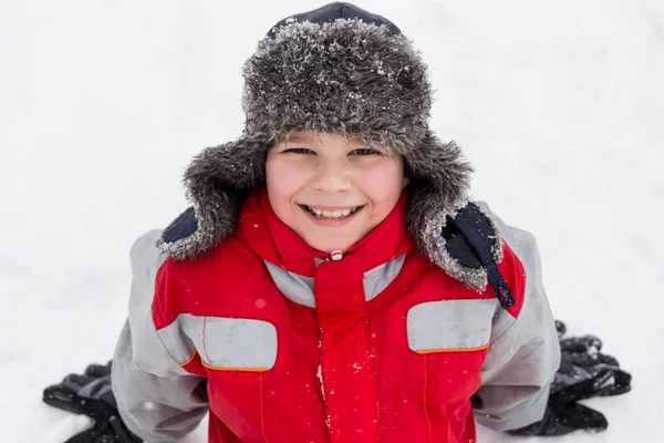 Roztomilý usměvavý chlapec sedí na sněhu — Stock fotografie