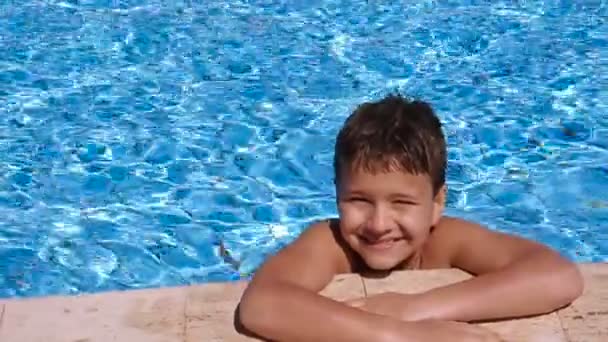 Garoto sorridente relaxante na piscina — Vídeo de Stock