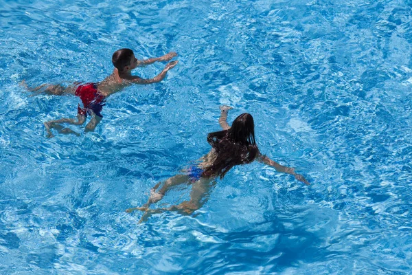 Двое детей плавают в бассейне вместе — стоковое фото