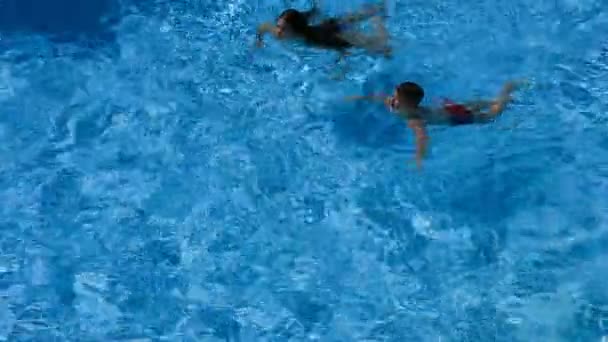 Двое детей плавают в бассейне вместе — стоковое видео