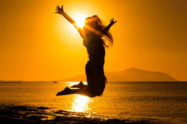 Silhueta de menina pulando contra o nascer do sol — Fotografia de Stock