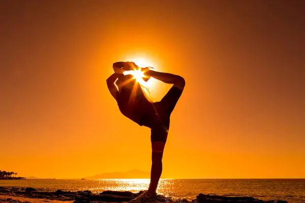 Silhouette of girl doing exercises at the coast Stock Photo