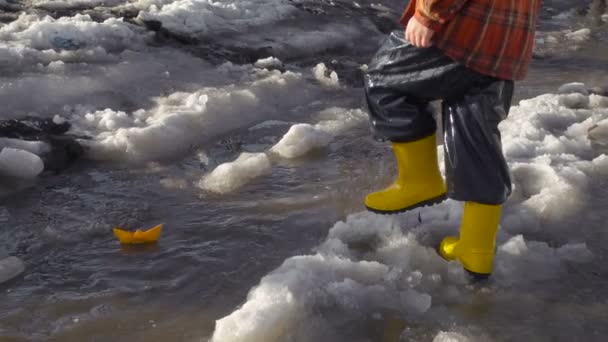 Menino lança um barco de papel no riacho da primavera — Vídeo de Stock