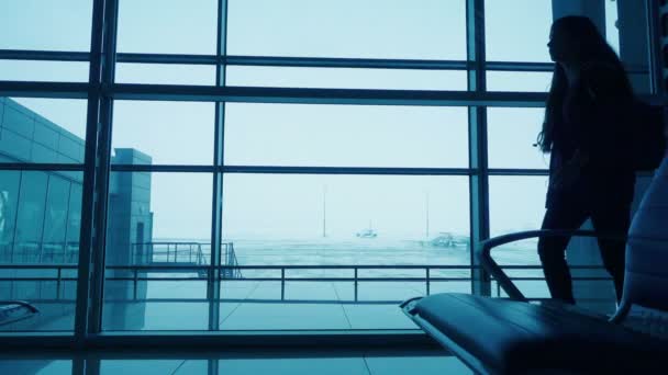 Силуэт девушки, идущей по терминалу аэропорта — стоковое видео