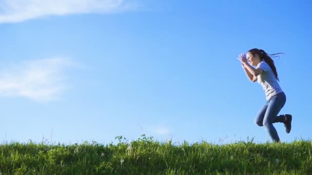 Menina feliz pulando na colina de grama verde — Vídeo de Stock