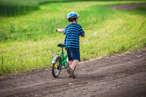 Mały chłopiec chodzenie pod górę z jego rower na wiejski krajobraz — Zdjęcie stockowe