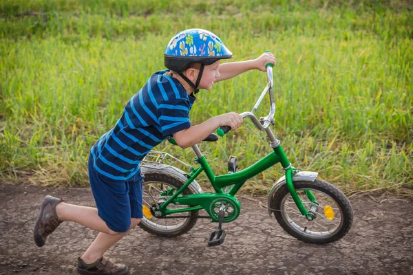 Niño corriendo con su bicicleta en las manos en el camino del campo —  Fotos de Stock