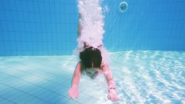 Молодая девушка ныряет в бассейн — стоковое видео