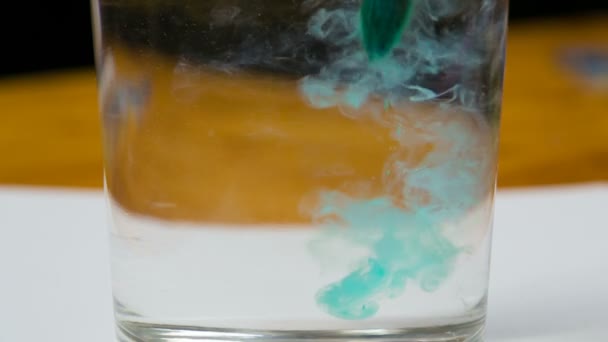 Green watercolor paint drops dissolve on water in glass — Stock Video