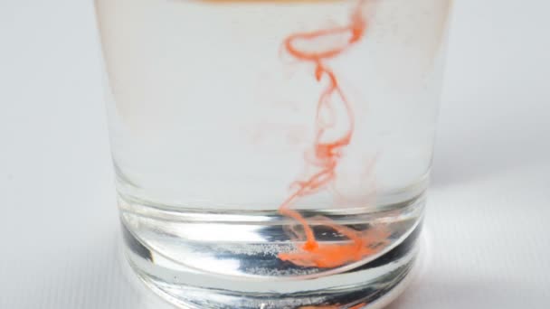 Orange watercolor paint drops dissolve on water in glass — Stock Video