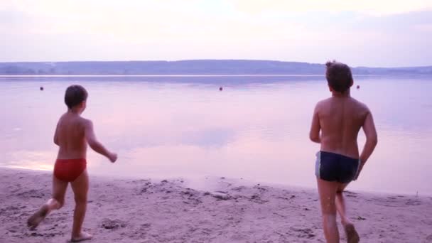 Silhouet van twee jongens lopen in het water — Stockvideo