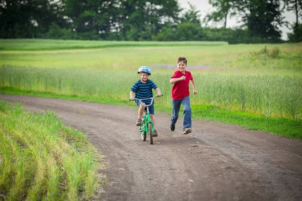 Duas crianças viajando junto com sua bicicleta na paisagem rural — Fotografia de Stock
