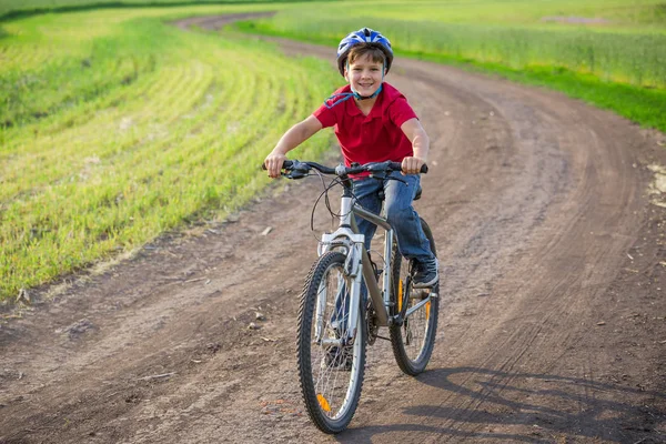 Passeio de menino na bicicleta na estrada rural — Fotografia de Stock