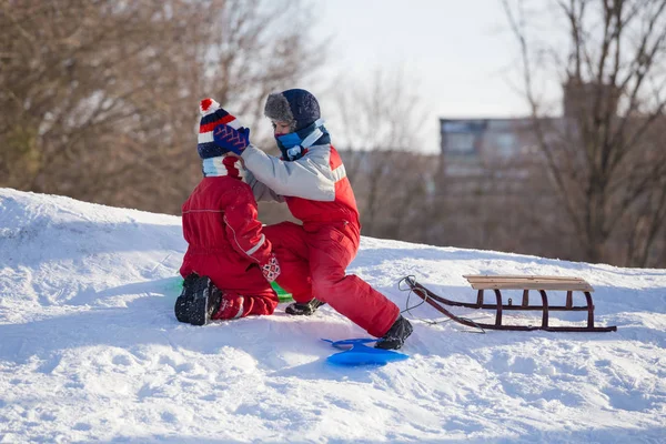 Older brother takes care of his younger brother on a snow hill — ストック写真