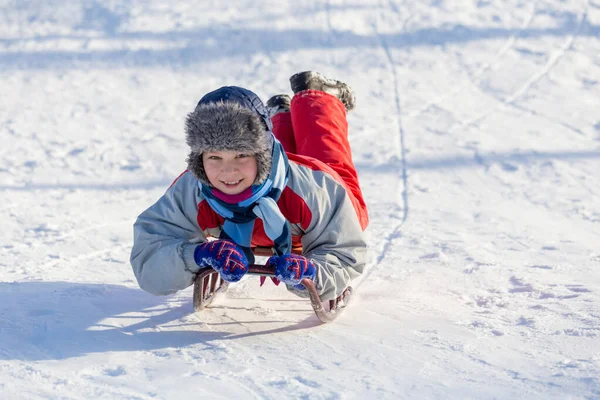 Mutlu çocuk kızak karlı tepe üzerinde sürme — Stok fotoğraf