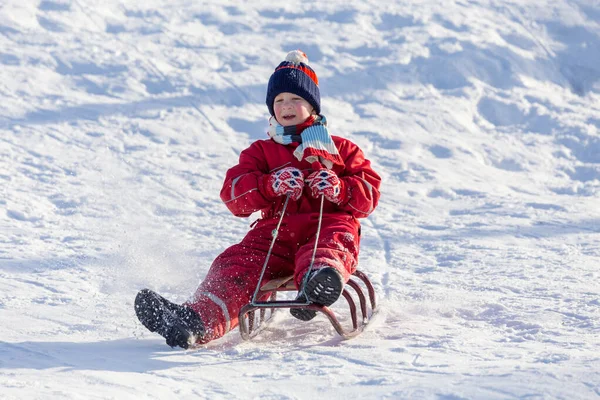 雪の丘の上のそりに座って幸せな少年は — ストック写真