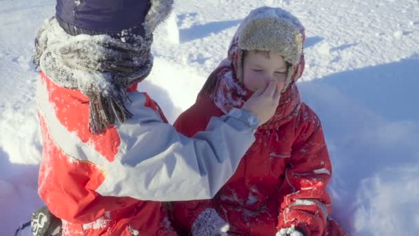 Két gyerek együtt játszik a téli parkban. — Stock videók