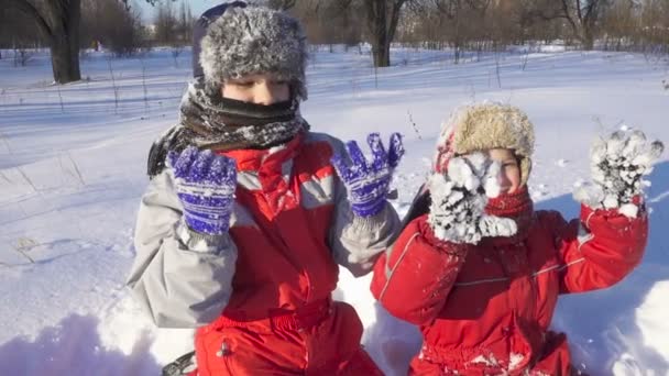Двое детей в зимнем парке показывают липкое снежное сияние — стоковое видео