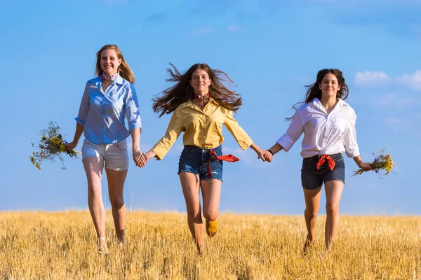 Three girls running on stubble field — Stock Photo, Image