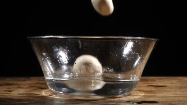 Champignons tombants dans un bol en verre sur une table en bois, au ralenti — Video