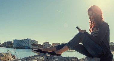 Deniz kenarındaki cep telefonuyla.