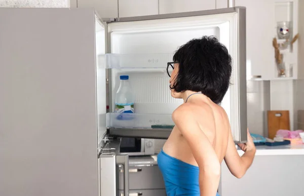 Mulher olhando para a geladeira — Fotografia de Stock