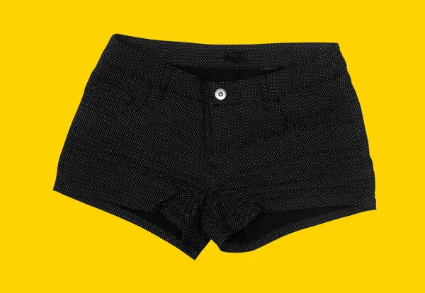 Weibliche schwarze Shorts auf gelbem Hintergrund — Stockfoto