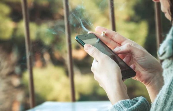 Nő a cigaretta használ a smartphone — Stock Fotó