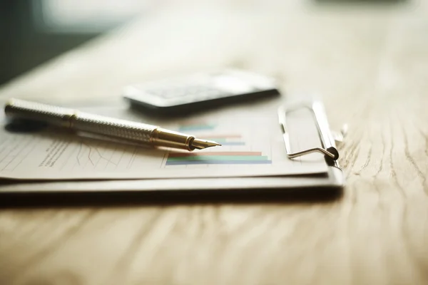 Caneta, calculadora e gráfico financeiro em um local de trabalho — Fotografia de Stock